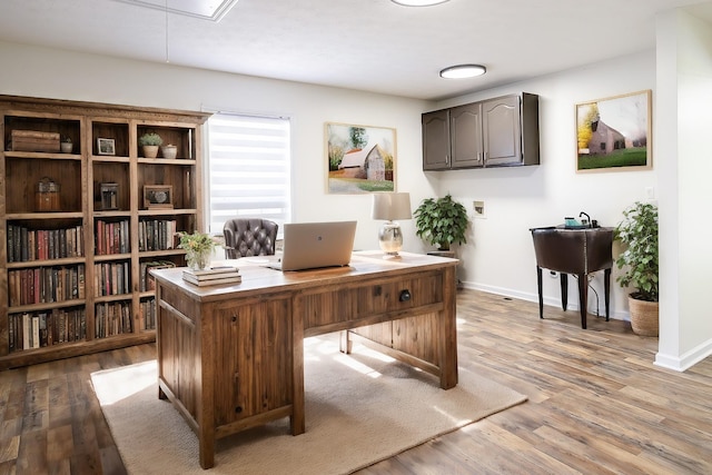 home office with attic access, baseboards, and light wood finished floors