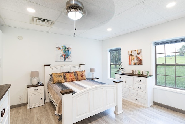 bedroom with light wood-style flooring, a drop ceiling, visible vents, and baseboards