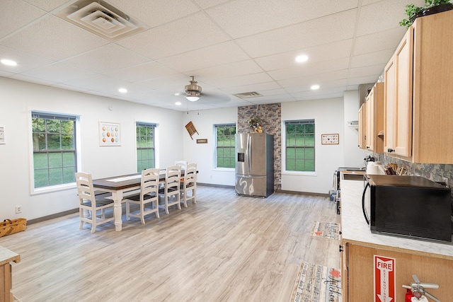 kitchen featuring stainless steel refrigerator with ice dispenser, visible vents, light countertops, light wood-style floors, and black microwave