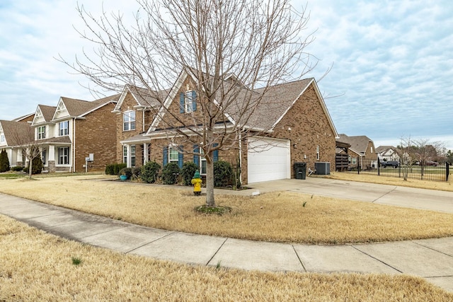 traditional-style house featuring a front yard, fence, concrete driveway, and brick siding