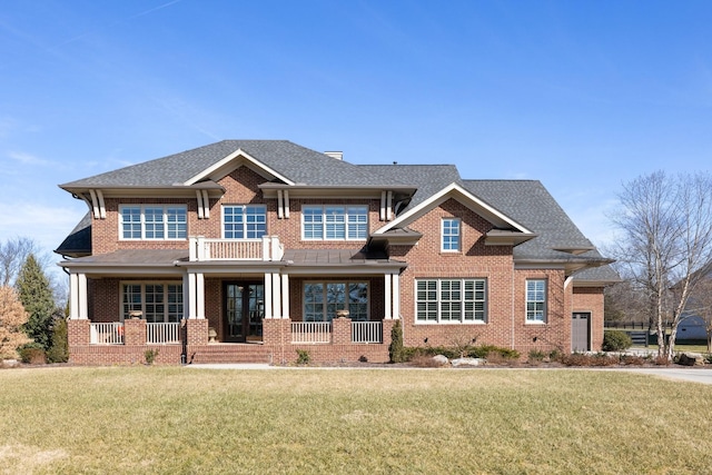 craftsman inspired home with a shingled roof, a front yard, covered porch, and brick siding