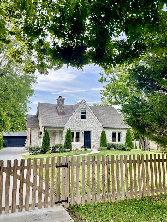 view of front facade featuring a fenced front yard, stone siding, a chimney, and a front lawn