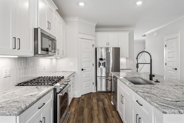 kitchen featuring white cabinets, light stone countertops, stainless steel appliances, and a sink