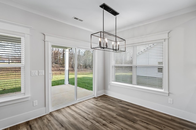 unfurnished dining area with baseboards, visible vents, a chandelier, and wood finished floors