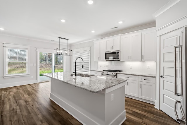 kitchen with appliances with stainless steel finishes, an island with sink, a sink, and white cabinets