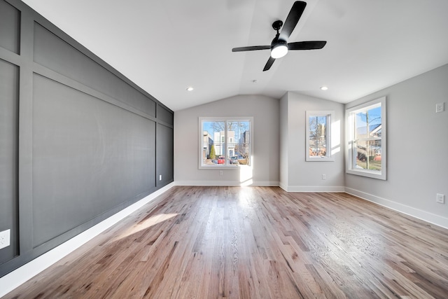 interior space featuring baseboards, a ceiling fan, vaulted ceiling, and light wood-type flooring