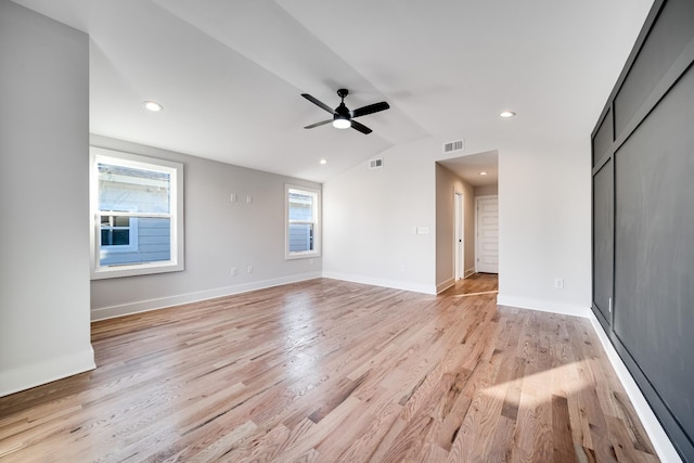 interior space featuring light wood finished floors, lofted ceiling, baseboards, visible vents, and ceiling fan