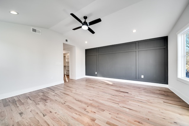 unfurnished room featuring light wood-type flooring, visible vents, vaulted ceiling, and a ceiling fan