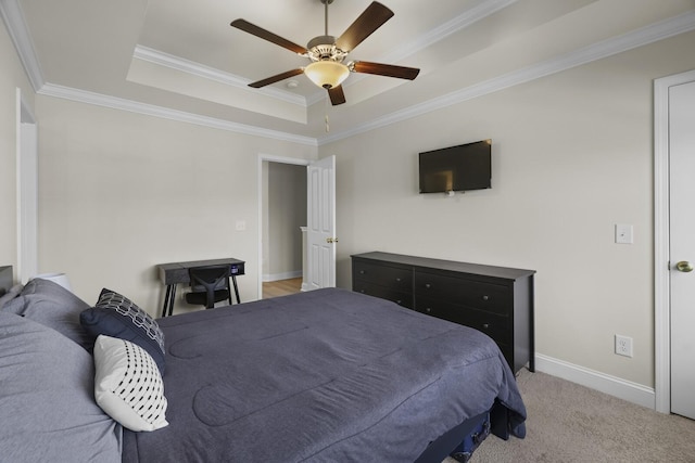 bedroom featuring light carpet, a ceiling fan, baseboards, ornamental molding, and a tray ceiling