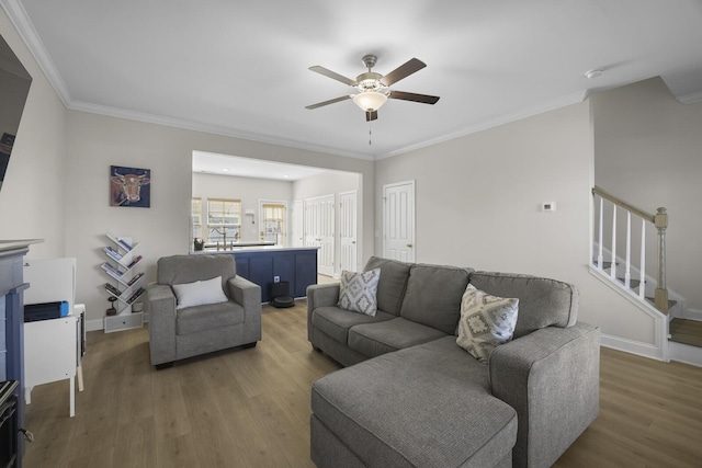 living room with baseboards, a ceiling fan, ornamental molding, wood finished floors, and stairs