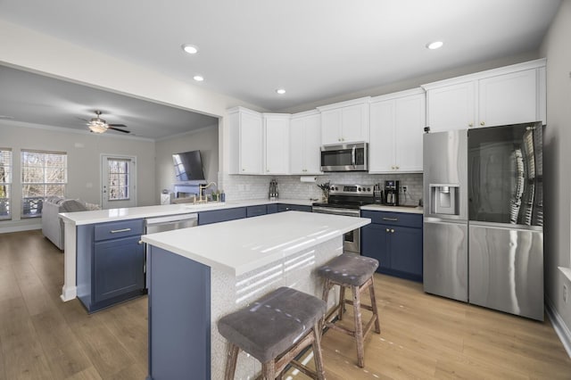 kitchen featuring light countertops, appliances with stainless steel finishes, blue cabinetry, and white cabinets