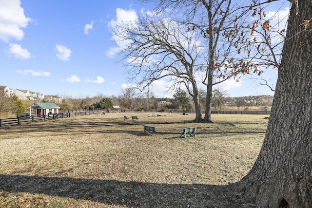 view of home's community with a yard, a rural view, and fence