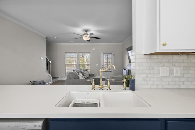 kitchen with crown molding, light countertops, white cabinets, a sink, and dishwasher