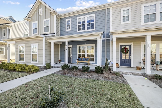 view of property with covered porch, a front lawn, and board and batten siding