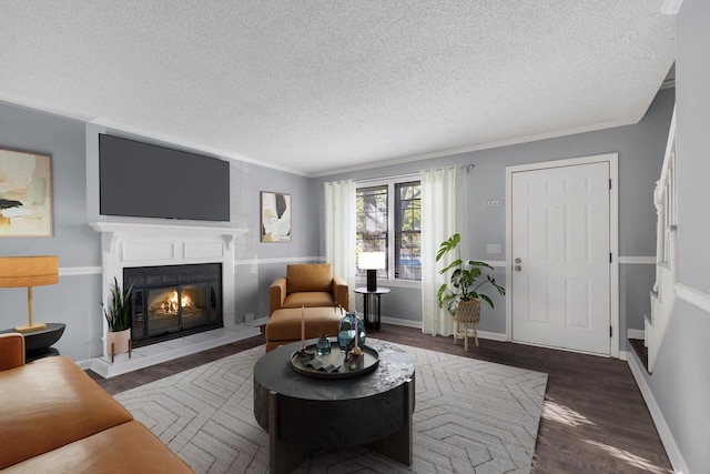 living room with a textured ceiling, a glass covered fireplace, wood finished floors, and baseboards