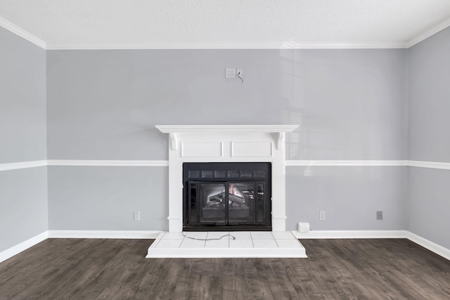 unfurnished living room with a fireplace with raised hearth, ornamental molding, wood finished floors, and baseboards