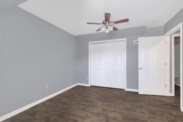 unfurnished bedroom with dark wood-type flooring, a closet, baseboards, and a ceiling fan