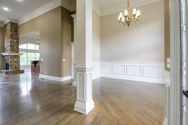 unfurnished dining area with dark wood-type flooring, crown molding, decorative columns, and a fireplace