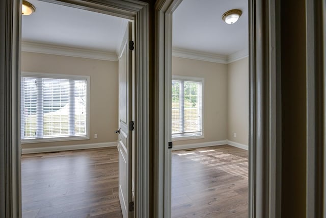 hallway featuring ornamental molding, baseboards, and wood finished floors