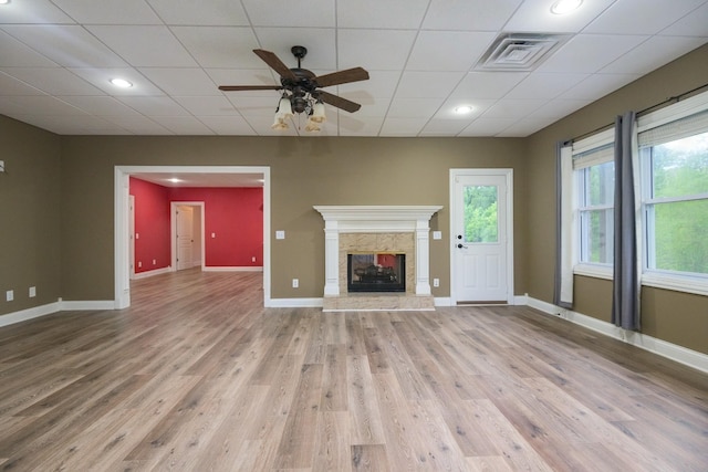 unfurnished living room featuring baseboards, visible vents, light wood-style flooring, and a high end fireplace