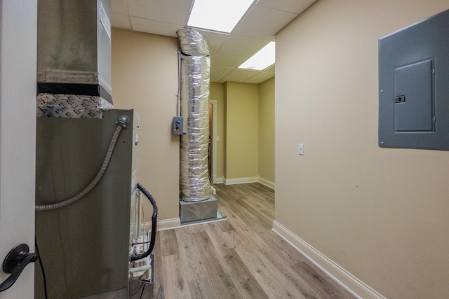 interior space with a paneled ceiling, light wood-style floors, electric panel, and baseboards