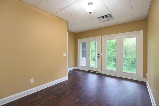 spare room with a paneled ceiling, dark wood finished floors, visible vents, and baseboards