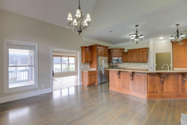 kitchen featuring appliances with stainless steel finishes, light countertops, a notable chandelier, and a breakfast bar area