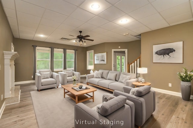 living area with a paneled ceiling, light wood-style floors, and baseboards