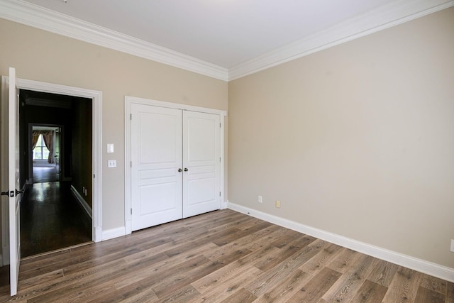 unfurnished bedroom with crown molding, wood finished floors, and baseboards