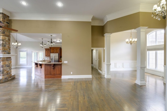 unfurnished living room with dark wood-type flooring, a chandelier, decorative columns, and ornamental molding