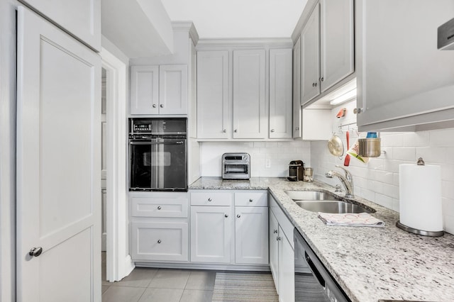 kitchen with light tile patterned floors, light stone counters, a sink, black appliances, and tasteful backsplash