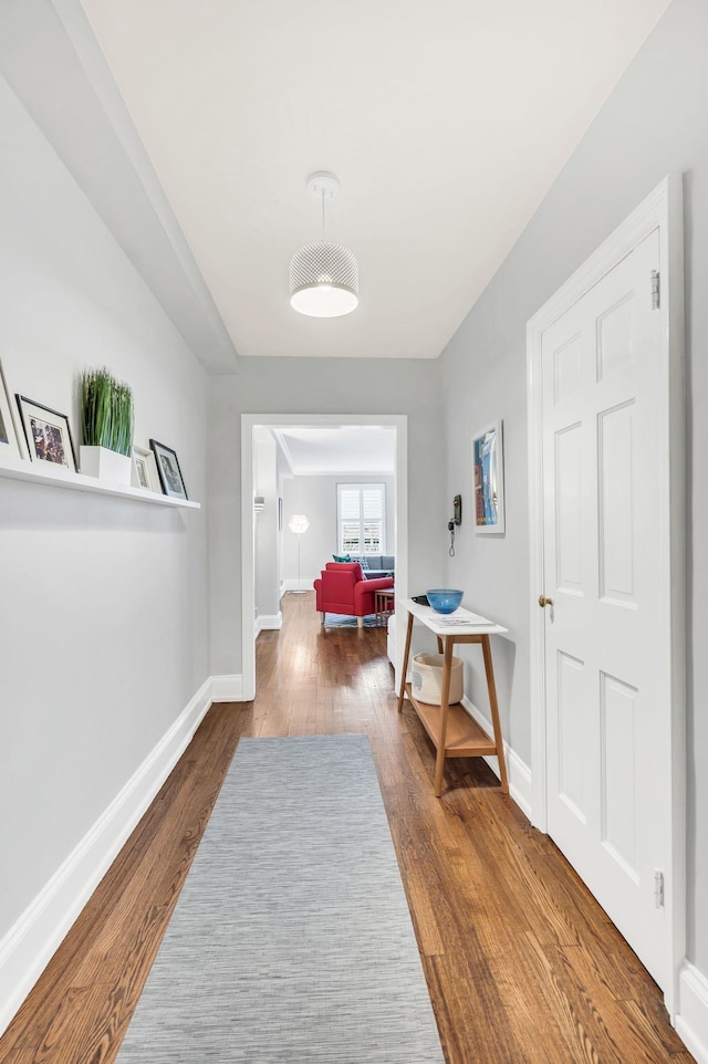 hall featuring dark wood-style flooring and baseboards