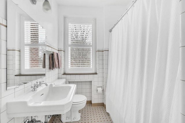 full bath featuring toilet, a sink, tile walls, and a shower with curtain