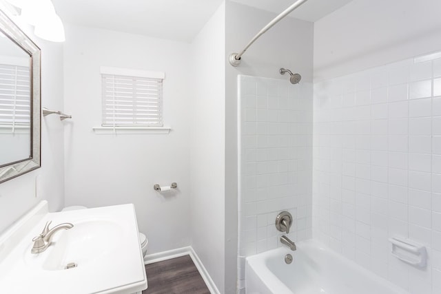 full bath with toilet, a sink, shower / tub combination, wood finished floors, and baseboards