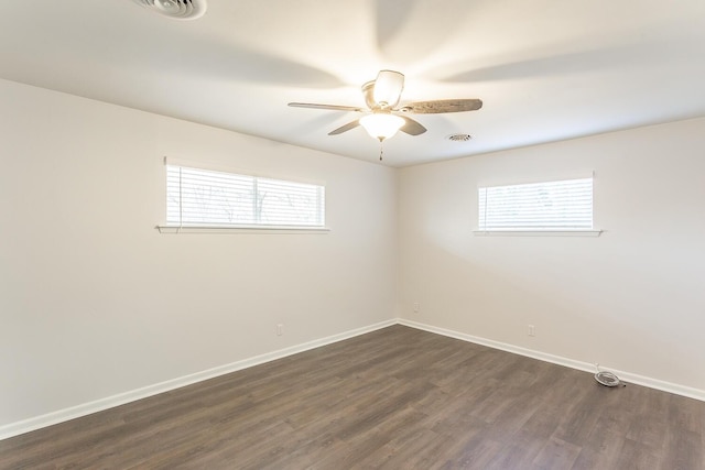 empty room with dark wood-type flooring, visible vents, ceiling fan, and baseboards