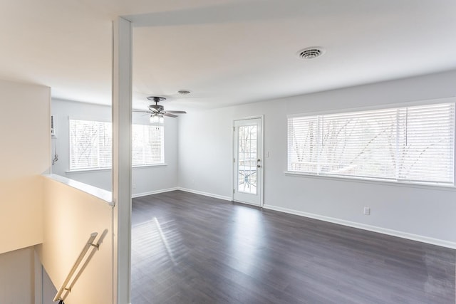 empty room with ceiling fan, dark wood-style flooring, visible vents, and baseboards