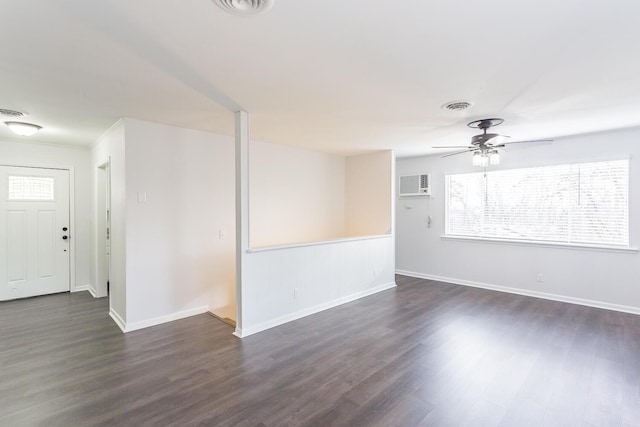 spare room with dark wood-type flooring, visible vents, baseboards, and a wall mounted AC