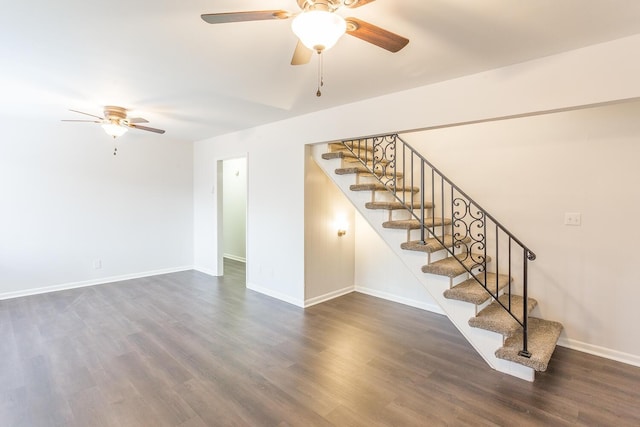 interior space with dark wood-style flooring, ceiling fan, baseboards, and stairs