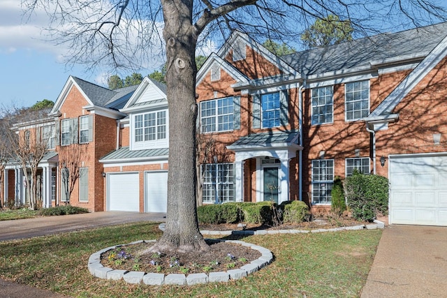 view of front of house featuring brick siding, a standing seam roof, metal roof, a garage, and driveway