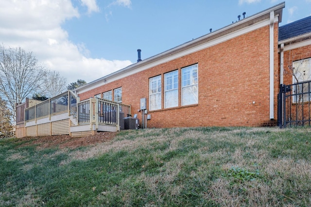 back of property with a deck, brick siding, and a lawn