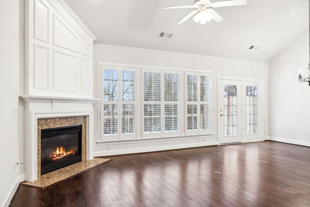 unfurnished living room with dark wood-style floors, a premium fireplace, visible vents, and a healthy amount of sunlight