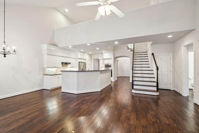 unfurnished living room featuring arched walkways, high vaulted ceiling, ceiling fan with notable chandelier, dark wood-style flooring, and baseboards