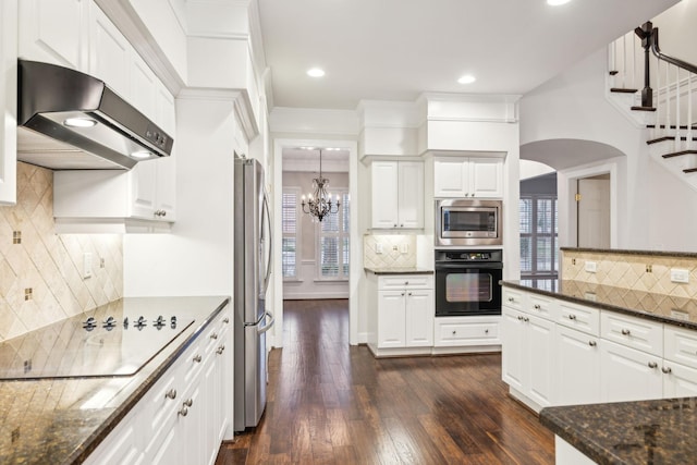 kitchen featuring tasteful backsplash, dark stone countertops, under cabinet range hood, black appliances, and white cabinetry