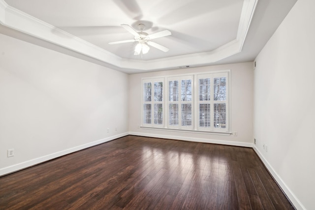 spare room featuring baseboards, a raised ceiling, and wood finished floors