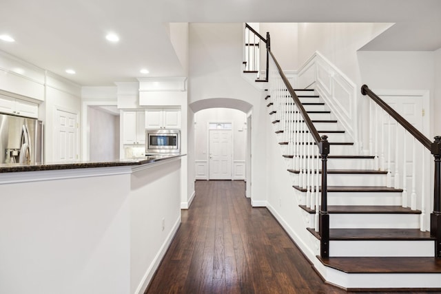 interior space with baseboards, arched walkways, wood finished floors, and recessed lighting