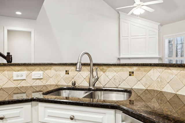 kitchen featuring tasteful backsplash, dark stone countertops, white cabinets, and a sink