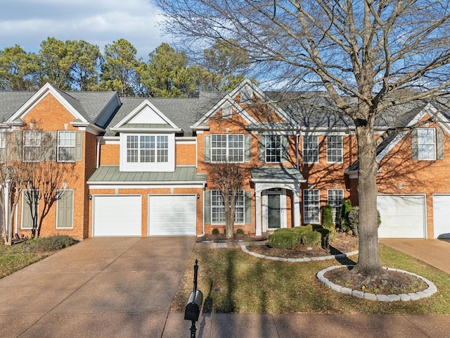 view of front of home with metal roof, an attached garage, brick siding, driveway, and a standing seam roof