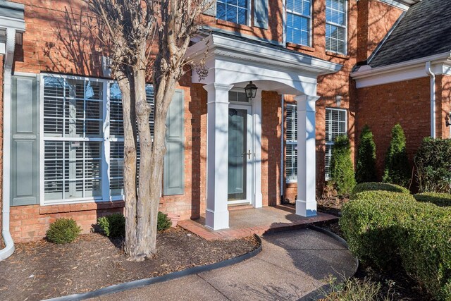 property entrance featuring brick siding and roof with shingles