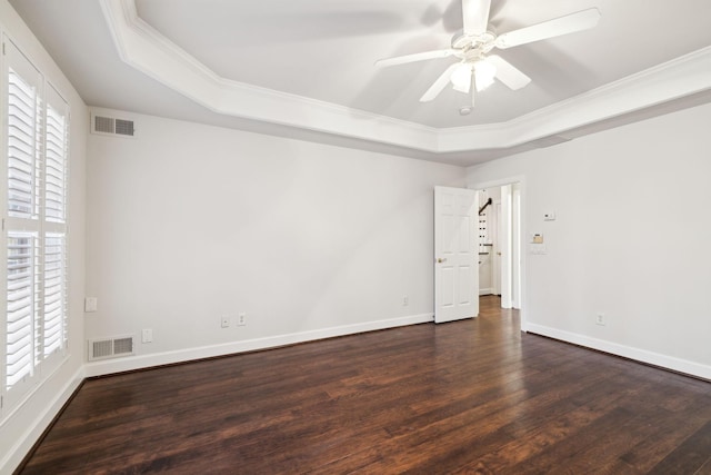 empty room with dark wood-style floors, a tray ceiling, and a wealth of natural light