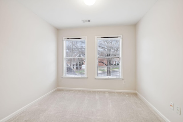 empty room with visible vents, light carpet, and baseboards